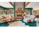 Spacious living room featuring a brick fireplace, large windows, comfortable seating, and green carpeting at 1332 Meadow Trl, Franktown, CO 80116