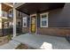 Inviting covered front porch featuring a yellow door, brick accents, and a concrete patio space at 8953 Southurst St, Littleton, CO 80129