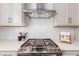 Close-up of a stainless steel gas range with a modern vent hood and white subway tile backsplash at 8953 Southurst St, Littleton, CO 80129