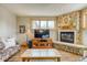 Inviting living room featuring stone fireplace and large TV, illuminated by natural light from wood-framed windows at 62 Broken Lance Dr # 202E, Breckenridge, CO 80424