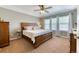 Spacious bedroom featuring a wooden bed frame, ceiling fan and sunlit windows, offering a comfortable and relaxing retreat at 6365 Orion Ct # B, Arvada, CO 80403