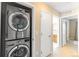 Hallway laundry closet featuring a stacked, front-loading washer and dryer for space-saving convenience at 1459 S Pierce St, Lakewood, CO 80232