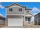 Two-story home boasts gray wood and stone accents, attached garage, and covered entryway at 864 Leeward St, Lochbuie, CO 80603