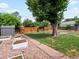Landscaped backyard featuring a large tree, shed, garden boxes, and wood storage at 1670 Oakland St, Aurora, CO 80010
