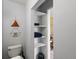 Bathroom featuring a toilet, open shelving with towels, and doorway leading to the bedroom with a gold trimmed mirror at 1670 Oakland St, Aurora, CO 80010