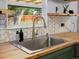 Close-up of kitchen sink with butcher block countertop and view to fenced backyard at 1670 Oakland St, Aurora, CO 80010