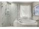 Modern bathroom featuring marble tile, glass enclosed shower and garden tub at 5964 E 141St Ave, Thornton, CO 80602