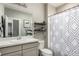 Neutral bathroom with a geometric patterned shower curtain, framed wall art, shelves, and a basin sink at 5964 E 141St Ave, Thornton, CO 80602