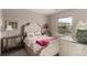 Cozy bedroom with tufted headboard, floral bedding, and sunlit window at 5964 E 141St Ave, Thornton, CO 80602