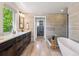 Primary bathroom with wood vanity, soaking tub, glass shower, and doorway to the walk-in closet at 1911 S Lafayette St, Denver, CO 80210
