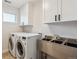 Laundry room with stainless steel sink, ample white cabinet storage, and front-loading washer and dryer at 1911 S Lafayette St, Denver, CO 80210