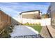 Snowy backyard area featuring a small patch of grass, privacy fence, and brick paved patio at 17938 E 54Th Ave, Denver, CO 80249