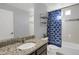 Bathroom boasts granite countertop vanity, mirror, and shower with blue patterned curtain and a toilet at 17938 E 54Th Ave, Denver, CO 80249