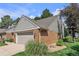 View of home featuring brick and horizontal siding, manicured lawn and gardens, along with a two-car garage at 7183 S Poplar St, Centennial, CO 80112