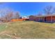 Spacious backyard featuring a well-kept lawn, wood fence, and a brick home with a covered patio, perfect for outdoor living at 383 S 21St Ave, Brighton, CO 80601