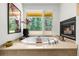 Bright bathroom boasting a soaking tub, garden view window and modern fireplace at 1250 Dolan Dr, Monument, CO 80132