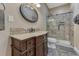 Bathroom featuring a wood vanity, oval mirror, tile backsplash, and glass shower enclosure at 12350 Turquoise Terrace St, Castle Pines, CO 80108