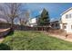 Picturesque backyard features lush green grass, wooden fence, mature trees, and a custom stone retaining wall at 1018 Mulberry Ln, Highlands Ranch, CO 80129