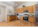 Well-lit kitchen featuring wooden cabinets, stainless steel appliances, and hardwood floors at 1018 Mulberry Ln, Highlands Ranch, CO 80129
