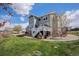 Expansive backyard with lush green grass, mature trees, and outdoor kitchen at 7692 Weaver Cir, Castle Rock, CO 80104