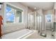 Clean bathroom with a glass shower enclosure, soaking tub under a large window, and tiled flooring at 7692 Weaver Cir, Castle Rock, CO 80104