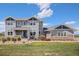 Inviting two-story home with gray siding and a covered front porch with stone accents and landscaped yard at 7692 Weaver Cir, Castle Rock, CO 80104