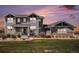 Charming two-story home with gray siding, stone accents, and a well-manicured lawn at dusk at 7692 Weaver Cir, Castle Rock, CO 80104