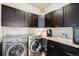 Well-equipped laundry room featuring dark wood cabinets, stainless steel appliances, and a convenient sink at 7692 Weaver Cir, Castle Rock, CO 80104