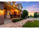 Inviting front porch with stone steps, brick pillars, and a manicured front yard showcasing lush green bushes at 7038 Russell Ct, Arvada, CO 80007