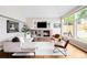 Cozy living room featuring a brick fireplace, built-in shelves, hardwood floors and large windows at 7038 Russell Ct, Arvada, CO 80007