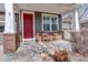 Inviting front porch with charming chairs, decorative wood carvings, and bright red front door at 15675 E Kettle Pl, Centennial, CO 80112