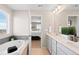 This bright bathroom has a soaking tub, dual sink vanity, and view into bedroom at 490 Silver Rock Trl, Castle Rock, CO 80104