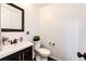 Cozy half bathroom with a dark wood vanity, white sink, and toilet at 10890 Willow Reed West Cir, Parker, CO 80134