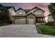 Two-story home boasts a stone facade, attached three-car garage, and a covered porch at 7949 S Elk Way, Aurora, CO 80016