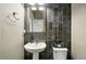 Stylish powder room featuring a pedestal sink, dark tile accent wall, and modern fixtures at 7949 S Elk Way, Aurora, CO 80016