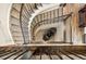 Aerial view of a curved carpeted staircase with dark metal railings and a modern chair at the bottom at 7949 S Elk Way, Aurora, CO 80016