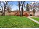 A well-maintained backyard featuring a wooden deck, lush lawn, storage shed, mature trees and brick home exterior at 60 Yarrow St, Lakewood, CO 80226
