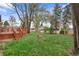 A well-maintained backyard featuring a wooden deck, lush lawn, mature trees and brick home exterior at 60 Yarrow St, Lakewood, CO 80226