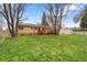 A well-maintained backyard featuring a wooden deck, lush lawn, storage shed, mature trees and brick home exterior at 60 Yarrow St, Lakewood, CO 80226