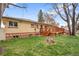A well-maintained backyard featuring a wooden deck, lush lawn, mature trees and brick home exterior at 60 Yarrow St, Lakewood, CO 80226