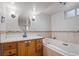 Charming bathroom featuring a wooden vanity, an oval mirror, and a soaking tub at 60 Yarrow St, Lakewood, CO 80226