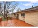 A view of the wooden deck, brick house exterior, and manicured yard at 60 Yarrow St, Lakewood, CO 80226
