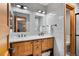 Well-lit bathroom featuring double sinks, wooden cabinetry, and a tile backsplash at 3816 Spring Valley Trl, Evergreen, CO 80439
