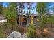 Stunning exterior view of a multi-level home nestled among tall trees and natural rock formations at 3816 Spring Valley Trl, Evergreen, CO 80439