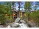 Beautiful exterior of a multi-level home surrounded by lush greenery, boulders and slight snow cover at 3816 Spring Valley Trl, Evergreen, CO 80439