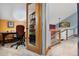 A bright home office with natural light, a desk, and a bookshelf with glass door at 3816 Spring Valley Trl, Evergreen, CO 80439