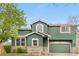 Beautiful two-story home with green stucco, stone accents, a two-car garage, and manicured landscaping at 2119 W 101St Cir, Thornton, CO 80260