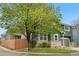 Green two-story home with a stone facade and a large, mature tree in the front yard at 2119 W 101St Cir, Thornton, CO 80260