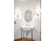Stylish powder room featuring a pedestal sink, oval mirror, and decorative wall sconces at 1437 Cassin Ct, Boulder, CO 80303