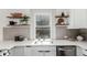 This kitchen features stainless appliances, floating shelves, a modern sink with a view, and white countertops and cabinetry at 2705 - 2707 N Lafayette St, Denver, CO 80205